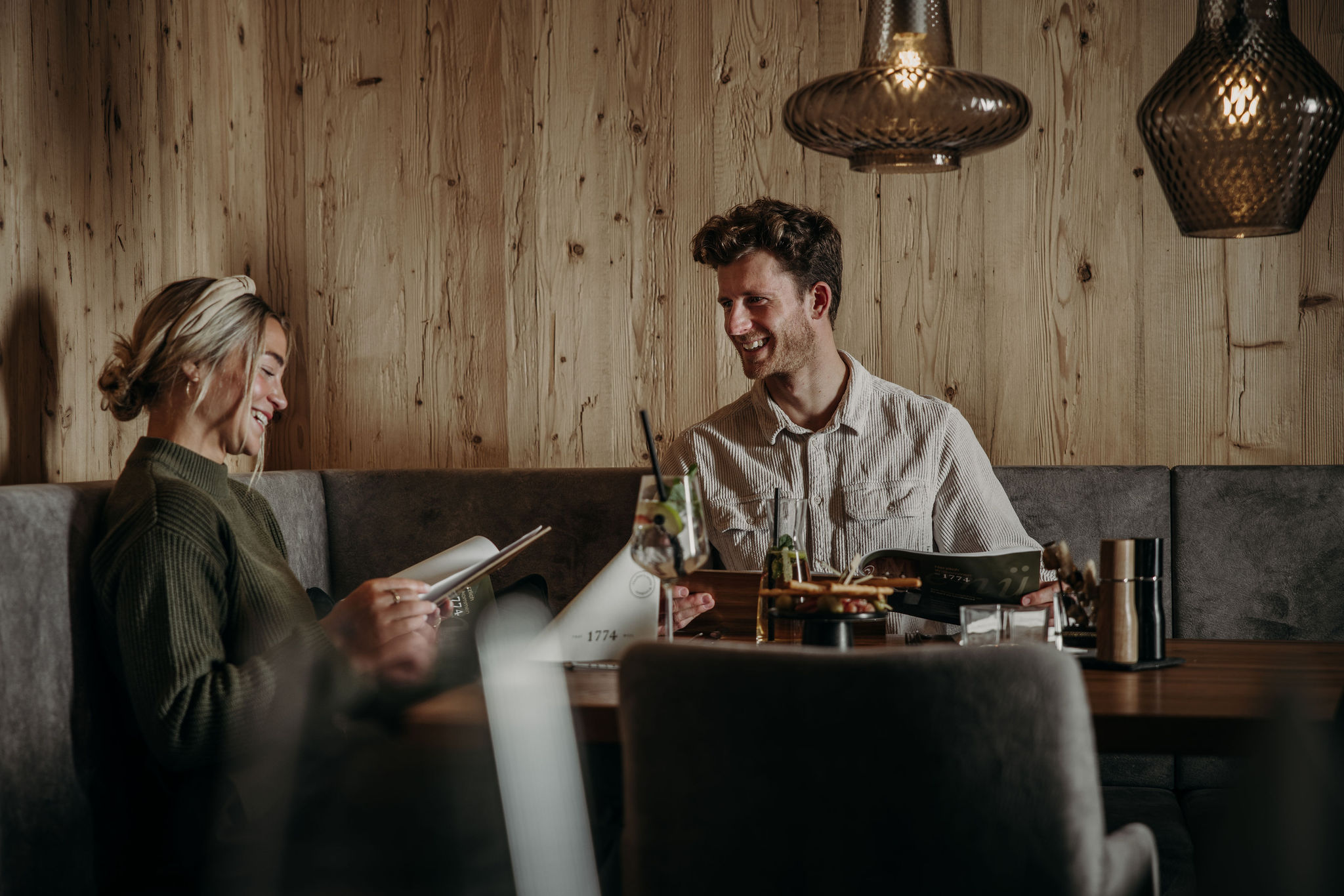 Zwei Personen sitzen lächelnd an einem Tisch in einem gemütlichen Restaurant